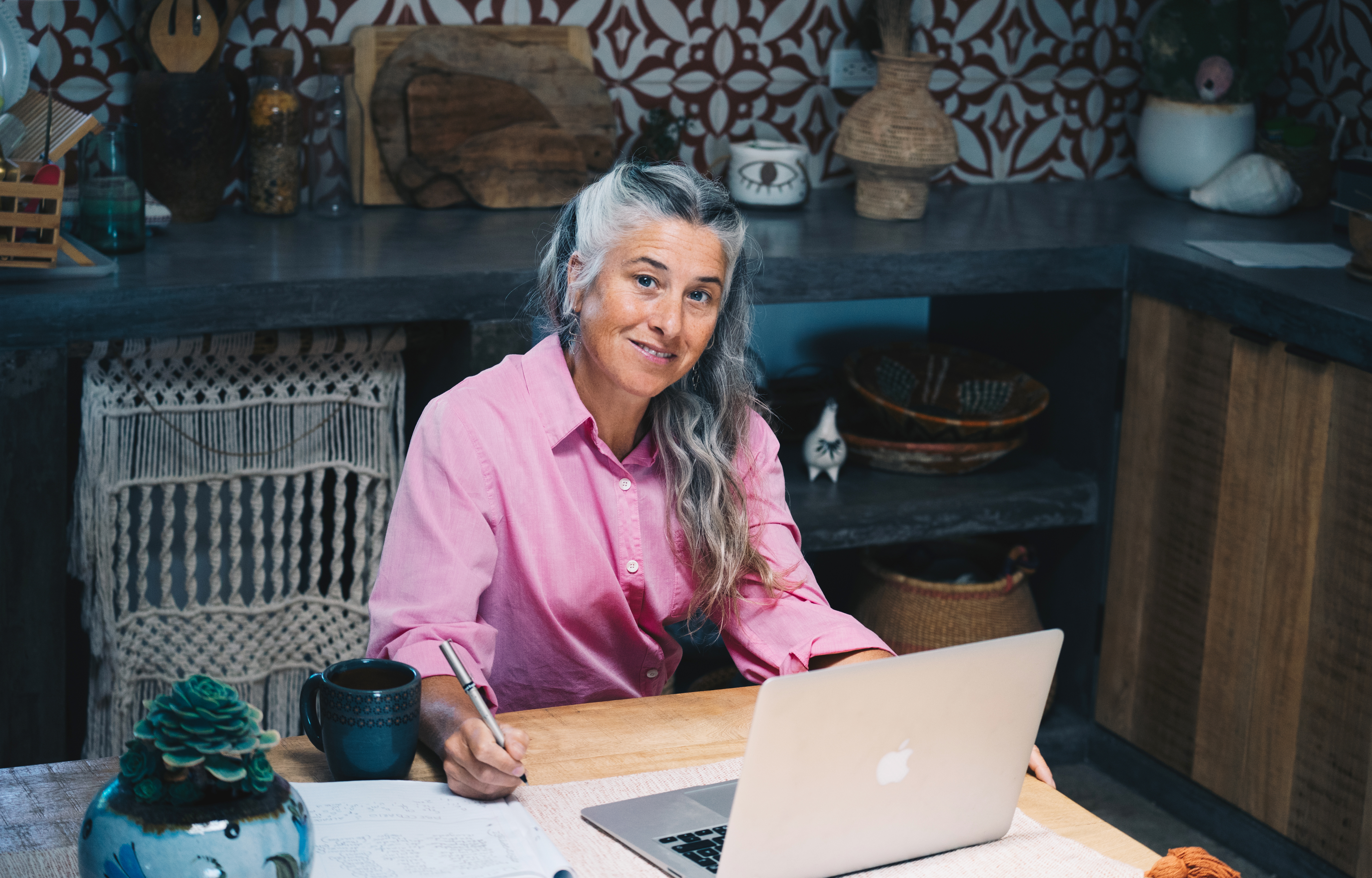 Geneviève Vena en chemise rose, à sa table de travail